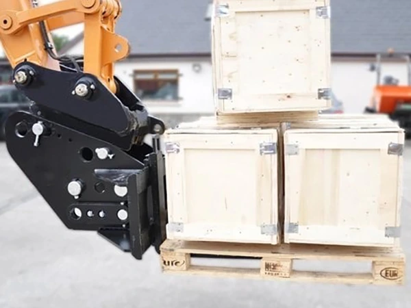 Excavator-mounted fork tines supporting palletised wooden crates