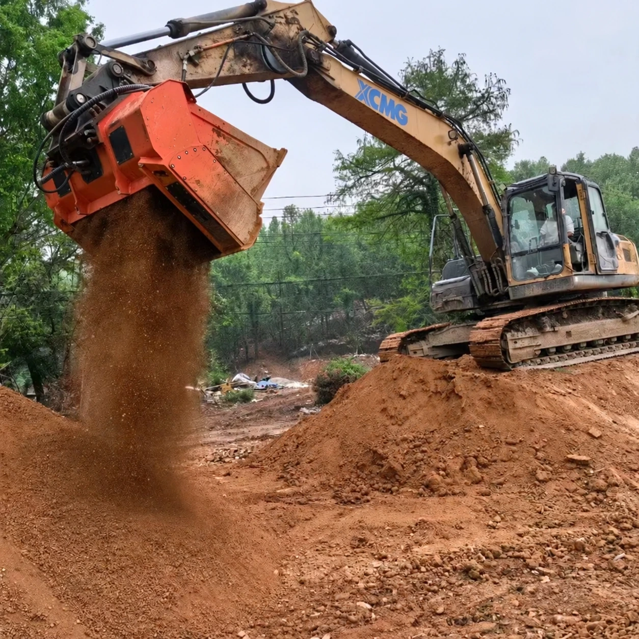 Excavator shaft screening bucket releasing screened soil on a construction site