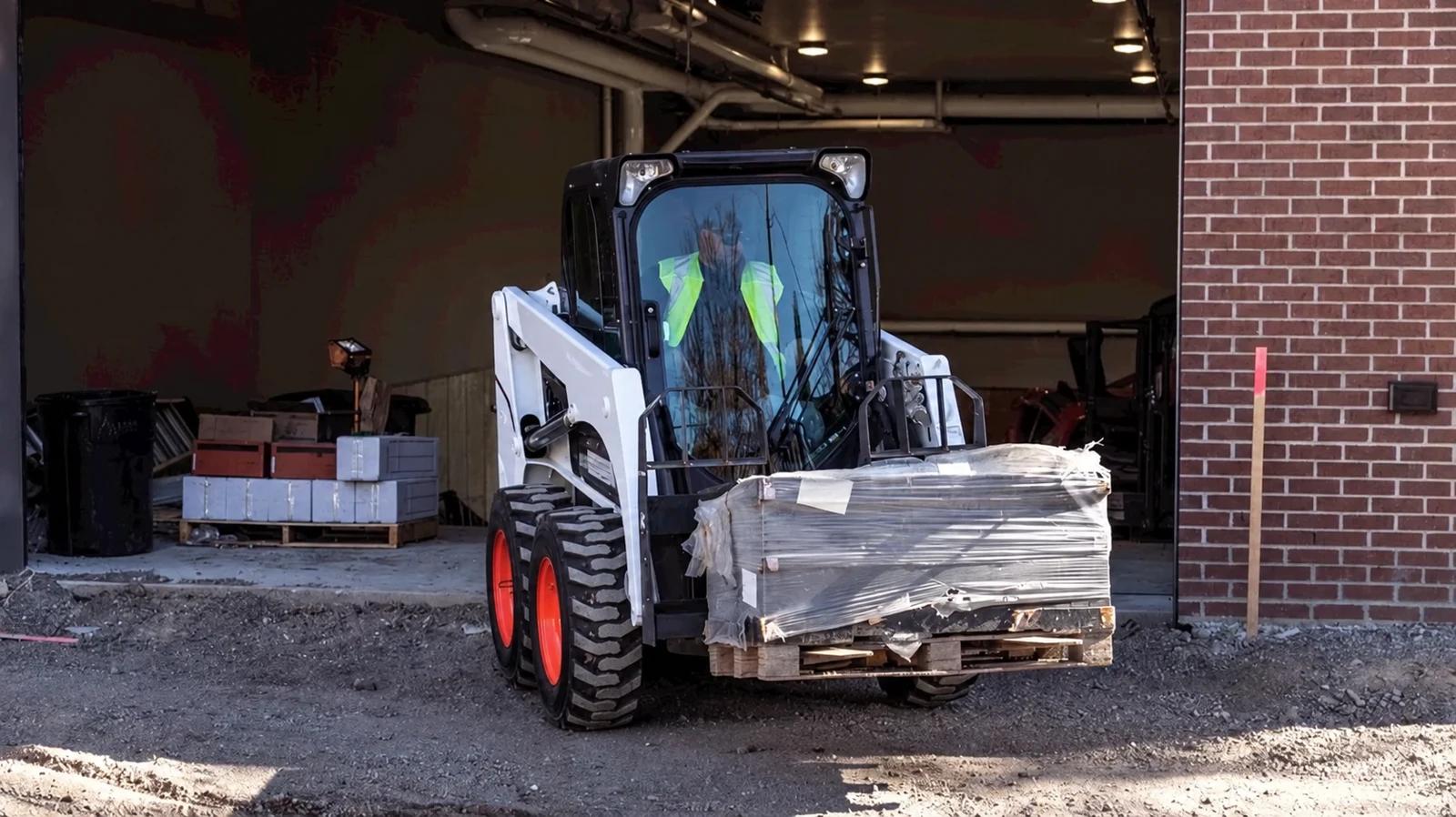 Wheeled skid-steer loader moving palletised materials