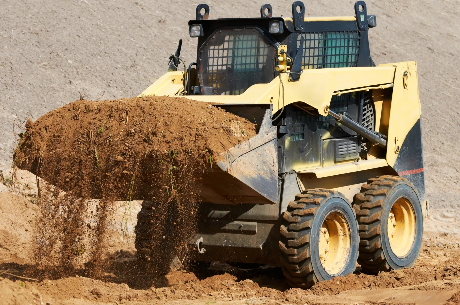 Wheeled skid-steer loader carrying loose soil