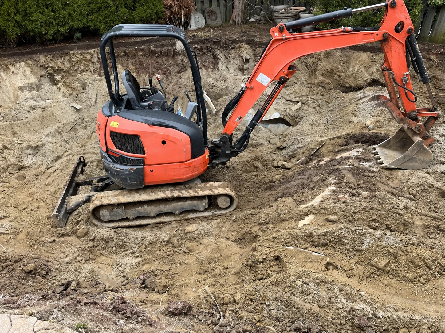 Compact excavator preparing soil at a residential site