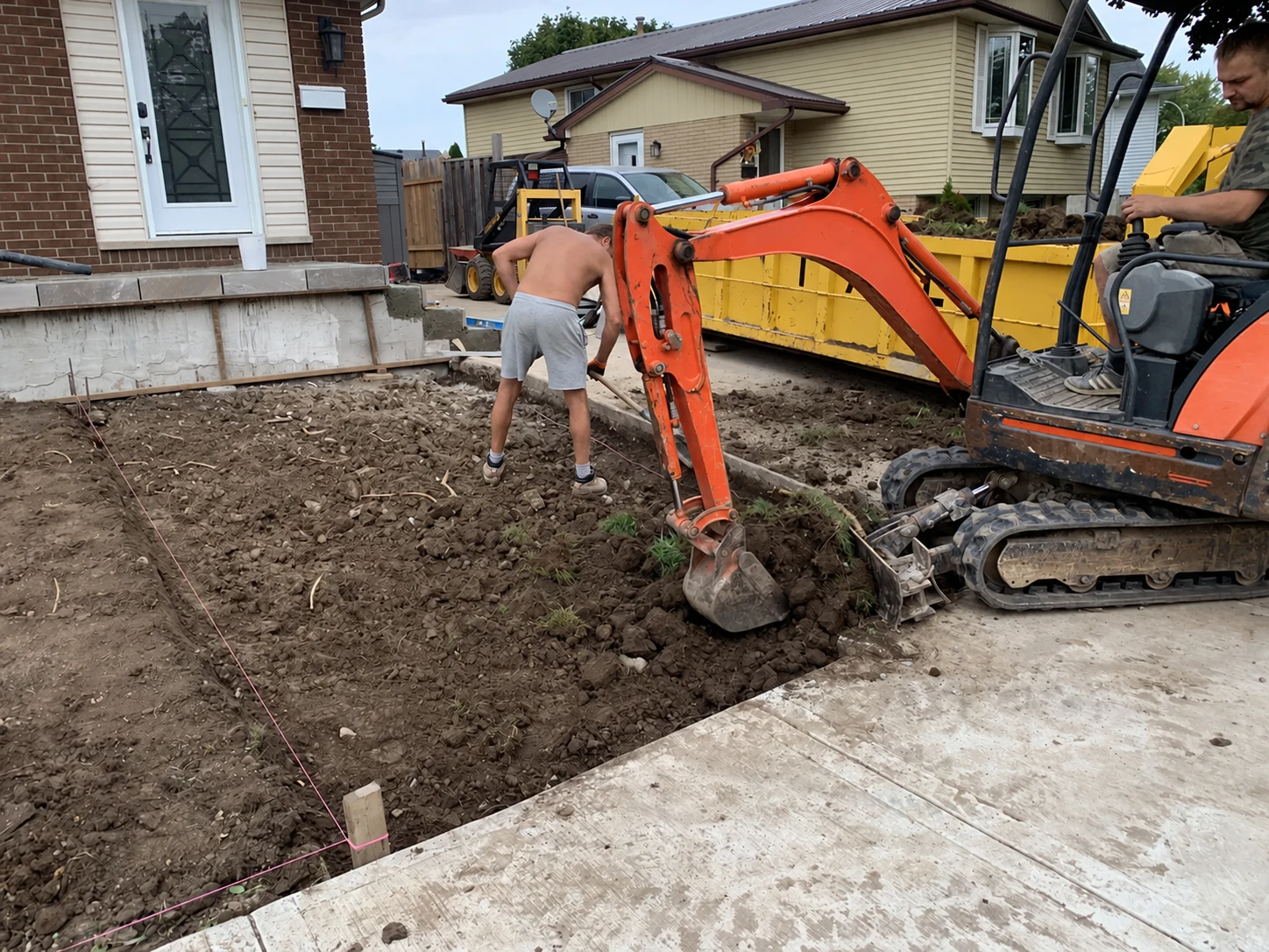 Compact excavator working beside a residential patio