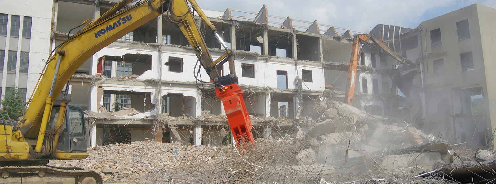 Excavator-mounted rotating concrete-processing jaws at a demolition site