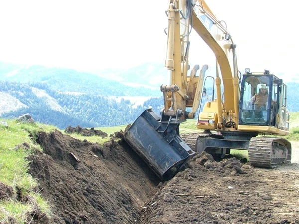 Hydraulically tilted bucket shaping a slope