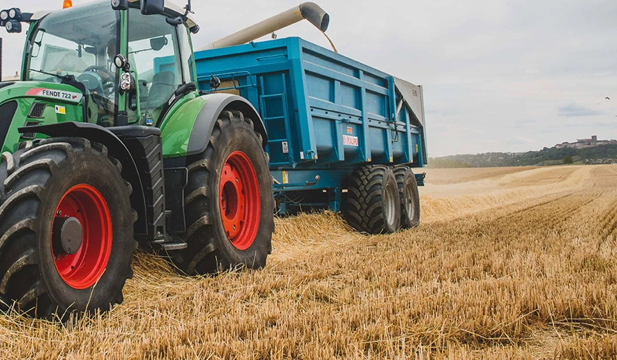 Tractor towing a farm trailer across a harvested field