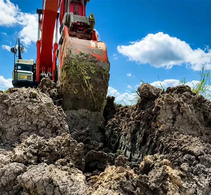 Excavator trenching bucket digging a narrow trench in soil