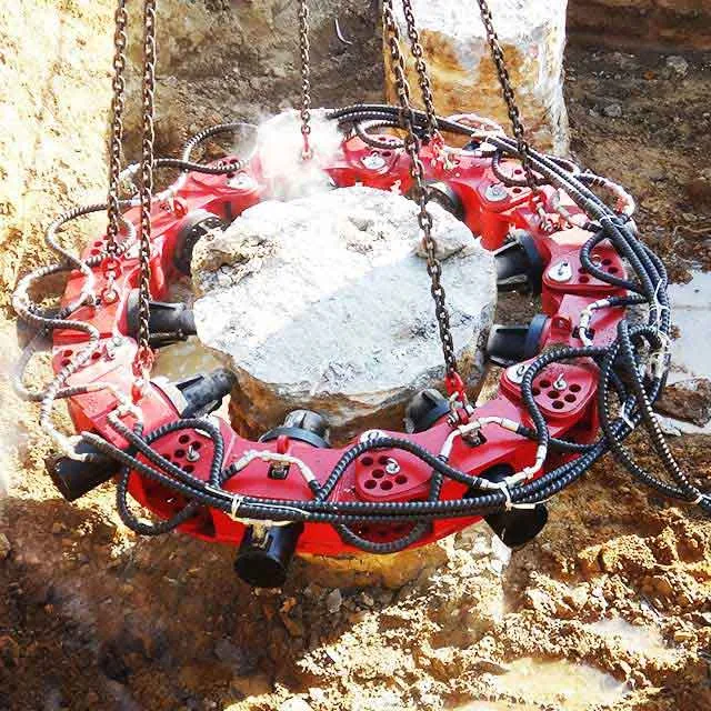 Suspended hydraulic pile breaker fracturing the head of a concrete pile at a construction site